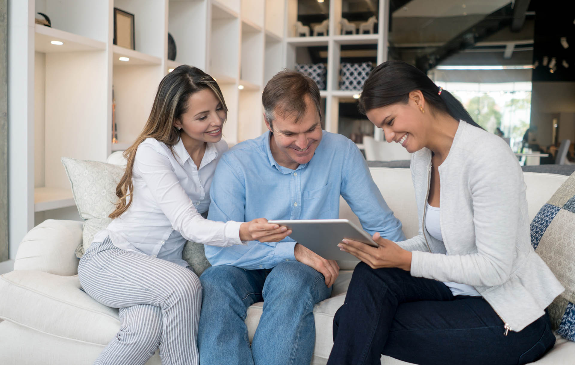 Couple shopping at a furniture store and saleswoman showing them a catalog on a tablet computer